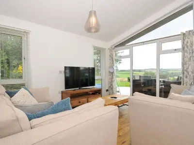 a living room with white furniture and a flat screen tv at 8 Horizon View in Liskeard
