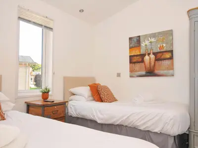 a bedroom with two beds and a painting on the wall at 8 Horizon View in Liskeard