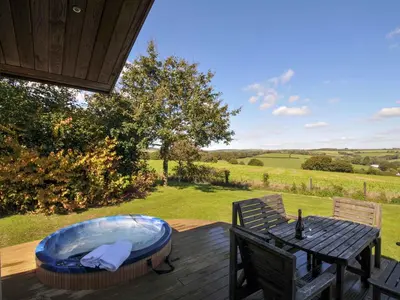 a wooden deck with a bench and a hot tub at 8 Horizon View in Liskeard