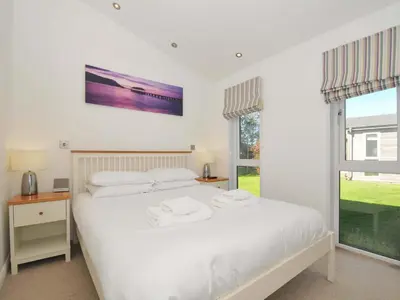 a white bedroom with a bed and a window at 10 Horizon View in Liskeard