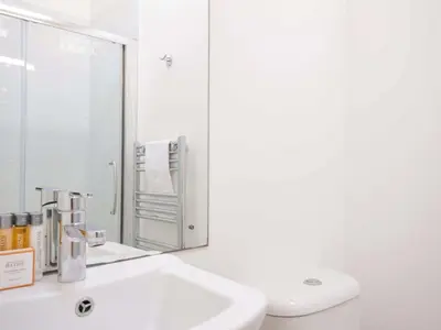 a white bathroom with a sink and a mirror at 10 Horizon View in Liskeard