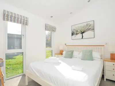 a bedroom with a white bed and two windows at 9 Horizon View in Liskeard