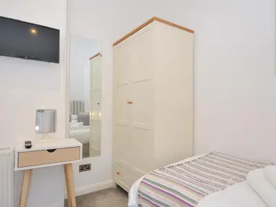 a white bedroom with a bed and a mirror at 9 Horizon View in Liskeard