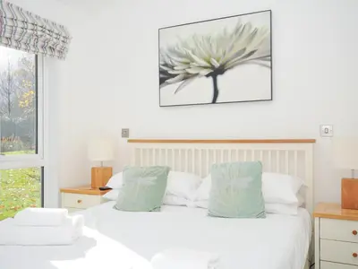 a bedroom with a white bed with a picture on the wall at 9 Horizon View in Liskeard