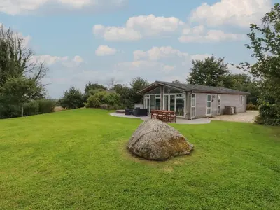 a large rock in the grass in front of a building at 9 Horizon View in Liskeard
