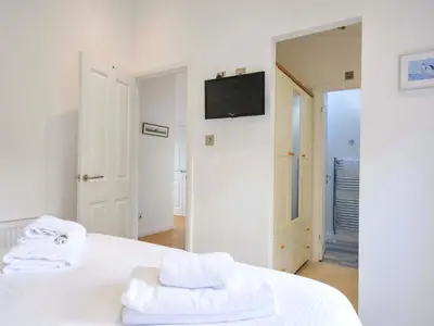 a white bedroom with two towels on a bed at 11 Horizon View in Liskeard