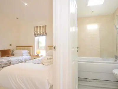 a bedroom with two beds and a tub and a sink at 11 Horizon View in Liskeard