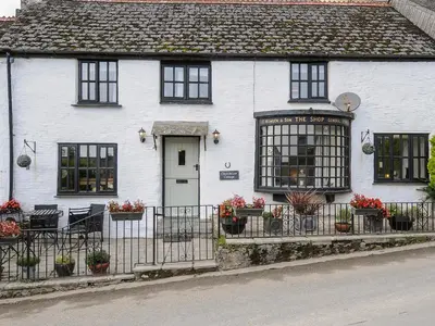 a white house with flowers in front of it at Church View Cottage in Looe