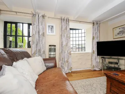 a living room with a couch and a flat screen tv at Church View Cottage in Looe
