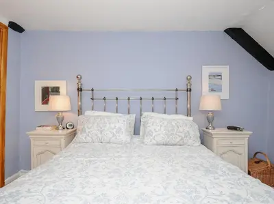 a bedroom with a large bed with blue walls at Church View Cottage in Looe