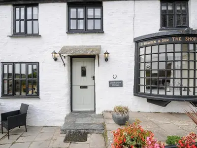 a white building with a door and a window at Church View Cottage in Looe