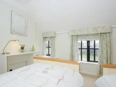 a white bedroom with a bed and a window at Church View Cottage in Looe
