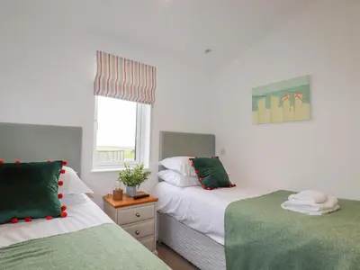 a bedroom with two beds with green and white sheets at 14 Horizon View in Liskeard