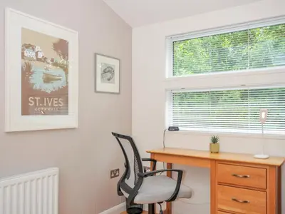 a desk and a chair in a room with a window at 15 Horizon View in Liskeard