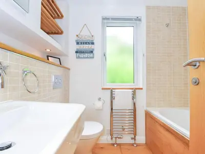 a bathroom with a sink and a toilet and a window at 15 Horizon View in Liskeard
