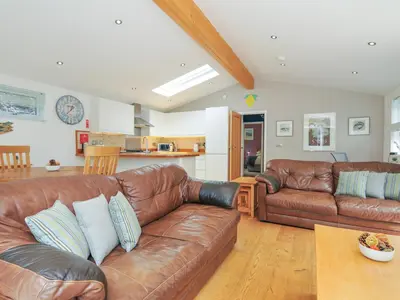 a living room with a brown leather couch and a table at 15 Horizon View in Liskeard