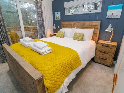 a bedroom with a large bed with a yellow blanket at 4 Faraway Fields in Liskeard