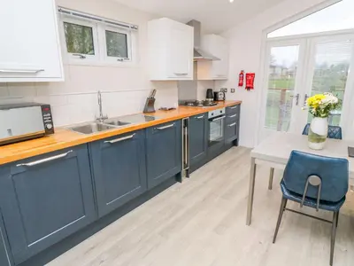 a kitchen with blue cabinets and a table at 4 Faraway Fields in Liskeard