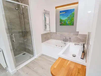 a white bathroom with a shower and a sink at 4 Faraway Fields in Liskeard