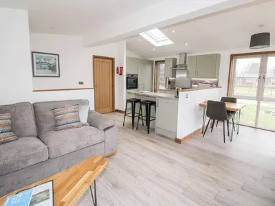 a living room with a couch and a kitchen at 2 Meadow Retreat in Liskeard