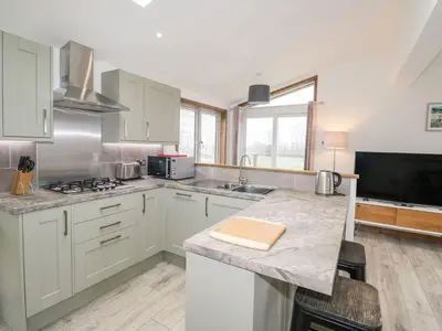 a kitchen with white cabinets and a counter top at 2 Meadow Retreat in Liskeard