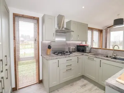 a kitchen with white cabinets and a stove top oven at 2 Meadow Retreat in Liskeard