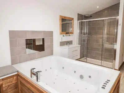 a bathroom with a large white tub and a shower at 2 Meadow Retreat in Liskeard