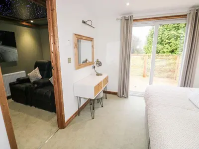 a bedroom with a bed and a desk and a mirror at 2 Meadow Retreat in Liskeard