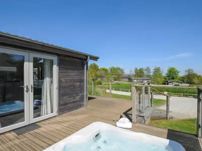 a hot tub on a deck next to a house at 5 Meadow Retreat in Liskeard