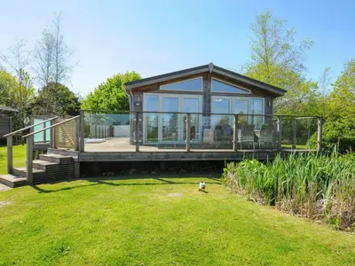a large glass house with a porch and a lawn at 5 Meadow Retreat in Liskeard