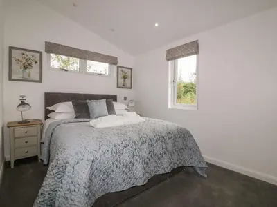 a bedroom with a bed and two windows at 7 Meadow Retreat in Liskeard