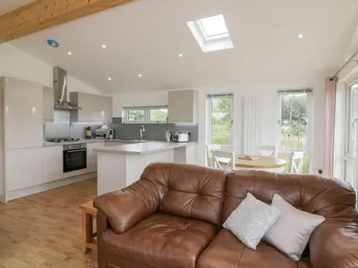 a living room with a brown leather couch in a kitchen at 7 Meadow Retreat in Liskeard