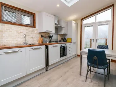a kitchen with white cabinets and a table and chairs at 2 Southern Place in Liskeard