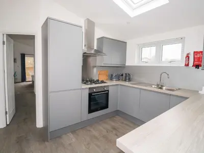 a white kitchen with a sink and a stove at 1 Southern Place in Liskeard