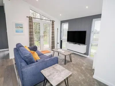 a living room with a blue couch and a tv at 1 Southern Place in Liskeard