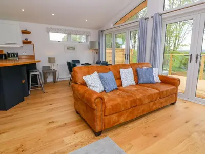 a living room with a brown couch with blue pillows at 21 Meadow Retreat in Liskeard