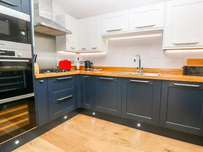 a kitchen with navy blue cabinets and wooden floors at 21 Meadow Retreat in Liskeard