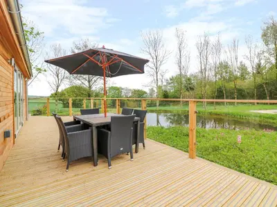 a deck with a table and chairs and an umbrella at 21 Meadow Retreat in Liskeard