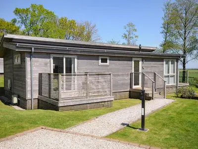 a small cabin with a porch on a grass field at 19 Meadow Retreat in Liskeard
