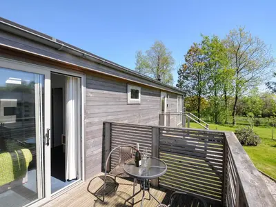 a patio with a table and chairs on a deck at 19 Meadow Retreat in Liskeard
