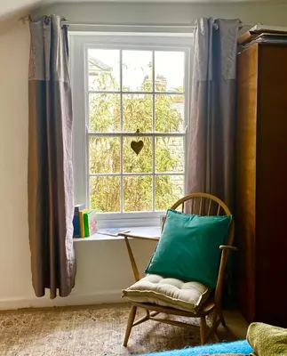 a chair sitting in front of a window with a pillow at Clarendon House in Saint Columb Major