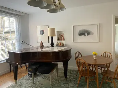 a piano in a living room with a table and chairs at Clarendon House in Saint Columb Major