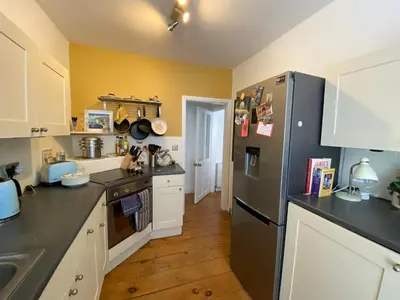 a kitchen with a black refrigerator and white cabinets at Clarendon House in Saint Columb Major