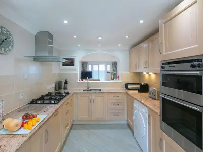 a large kitchen with wooden cabinets and a sink at Surf and Sand in St Ives