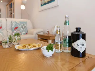 a table with a bottle of alcohol and a plate of food at Surf and Sand in St Ives