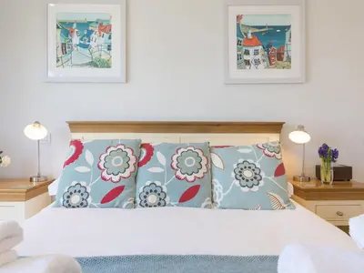 a bedroom with a white bed with blue and red pillows at Surf and Sand in St Ives