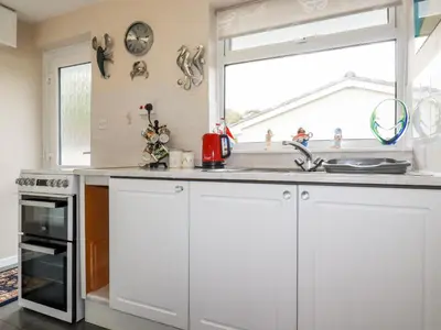 a kitchen with white cabinets and a window at Smugglers in Liskeard