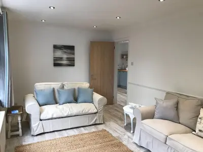 a living room with two white couches and blue pillows at The Retreat St Ives in St Ives