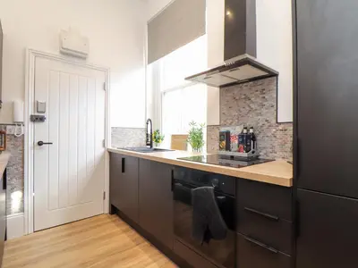 a kitchen with black cabinets and a sink and a window at The Dynar in Helston