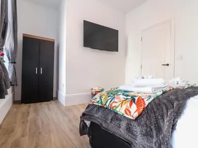 a bedroom with a bed and a flat screen tv on the wall at The Dynar in Helston